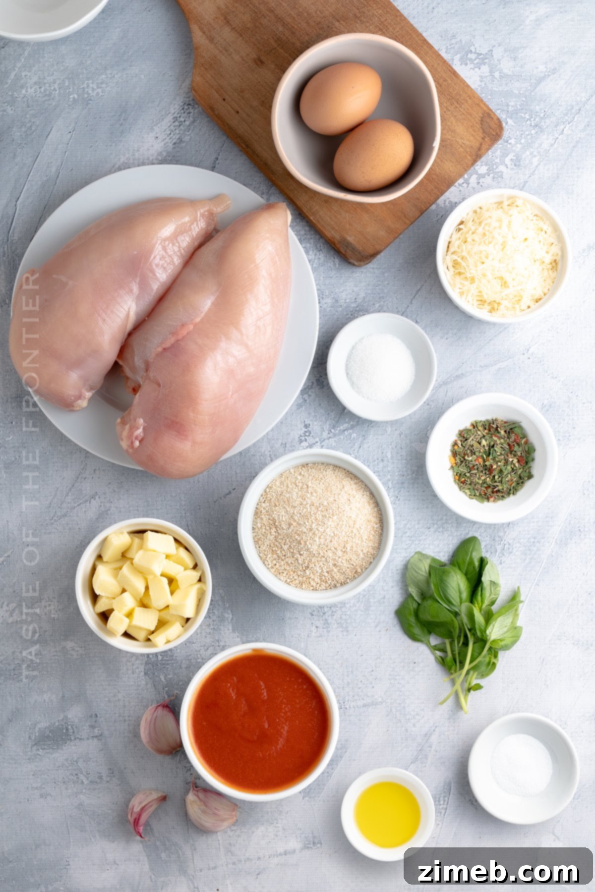 Fresh ingredients for a homemade Chicken Parmesan recipe, including chicken, tomatoes, and cheese.
