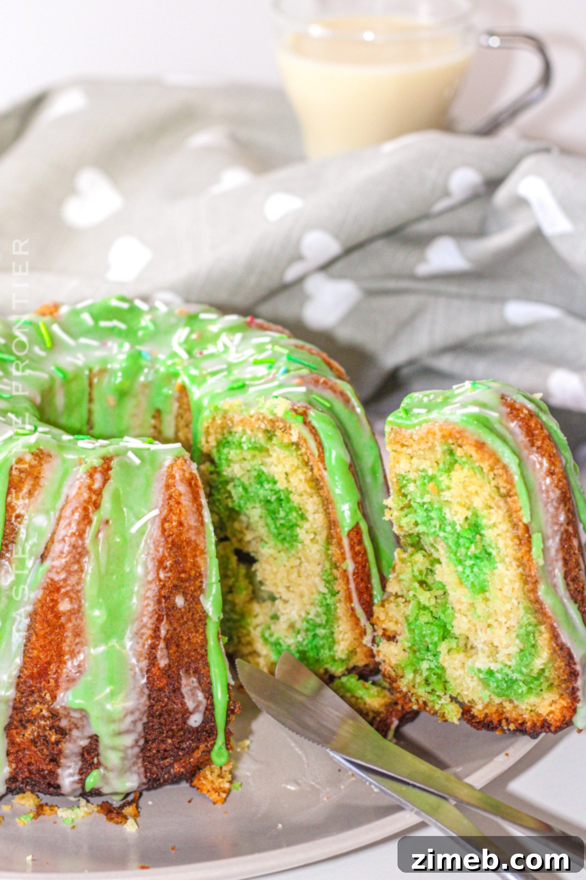 A beautiful slice of green bundt cake with white icing, showing the vibrant layers.