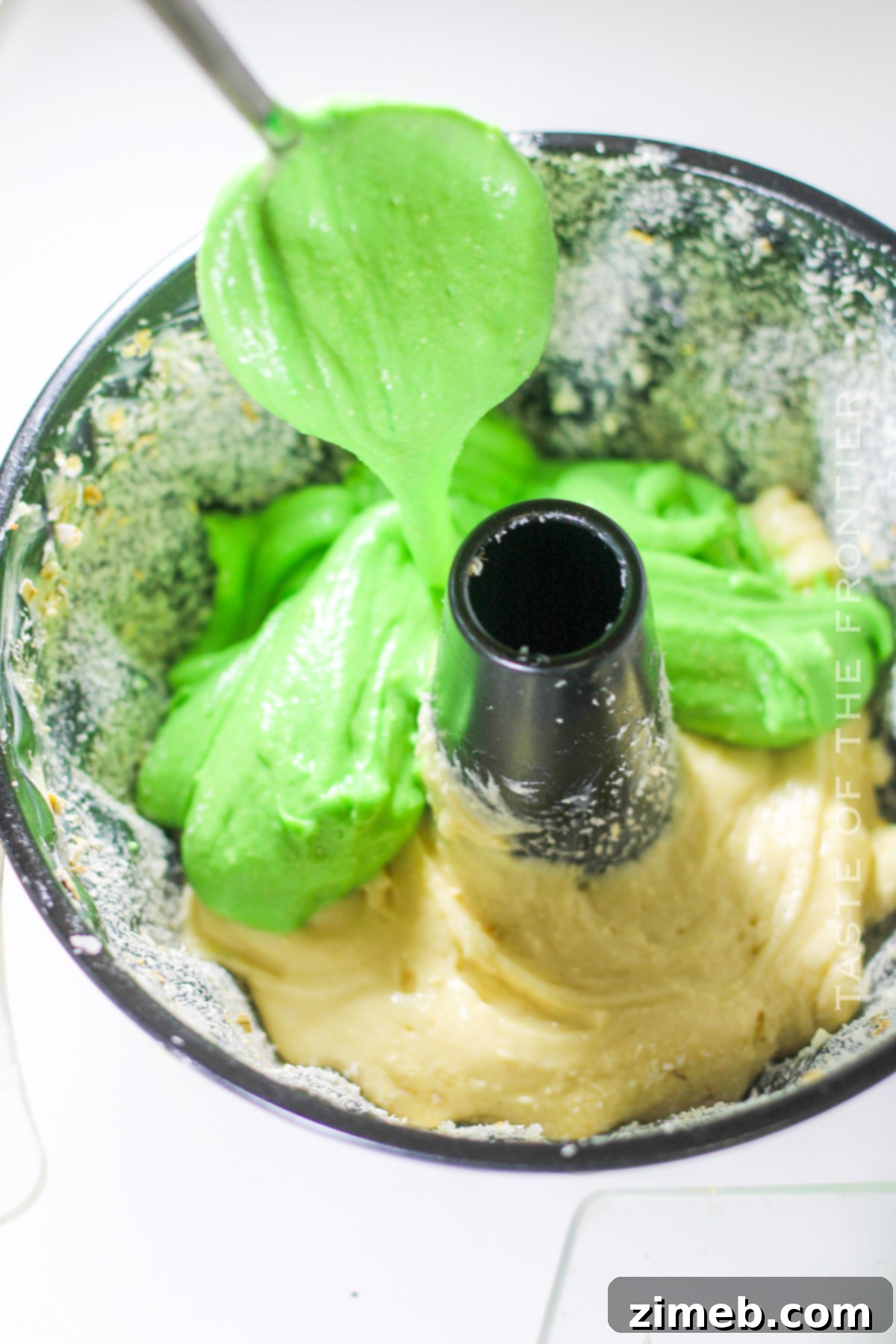 Layering green and white cake batter in a bundt pan to create a festive St. Patrick's Day cake.