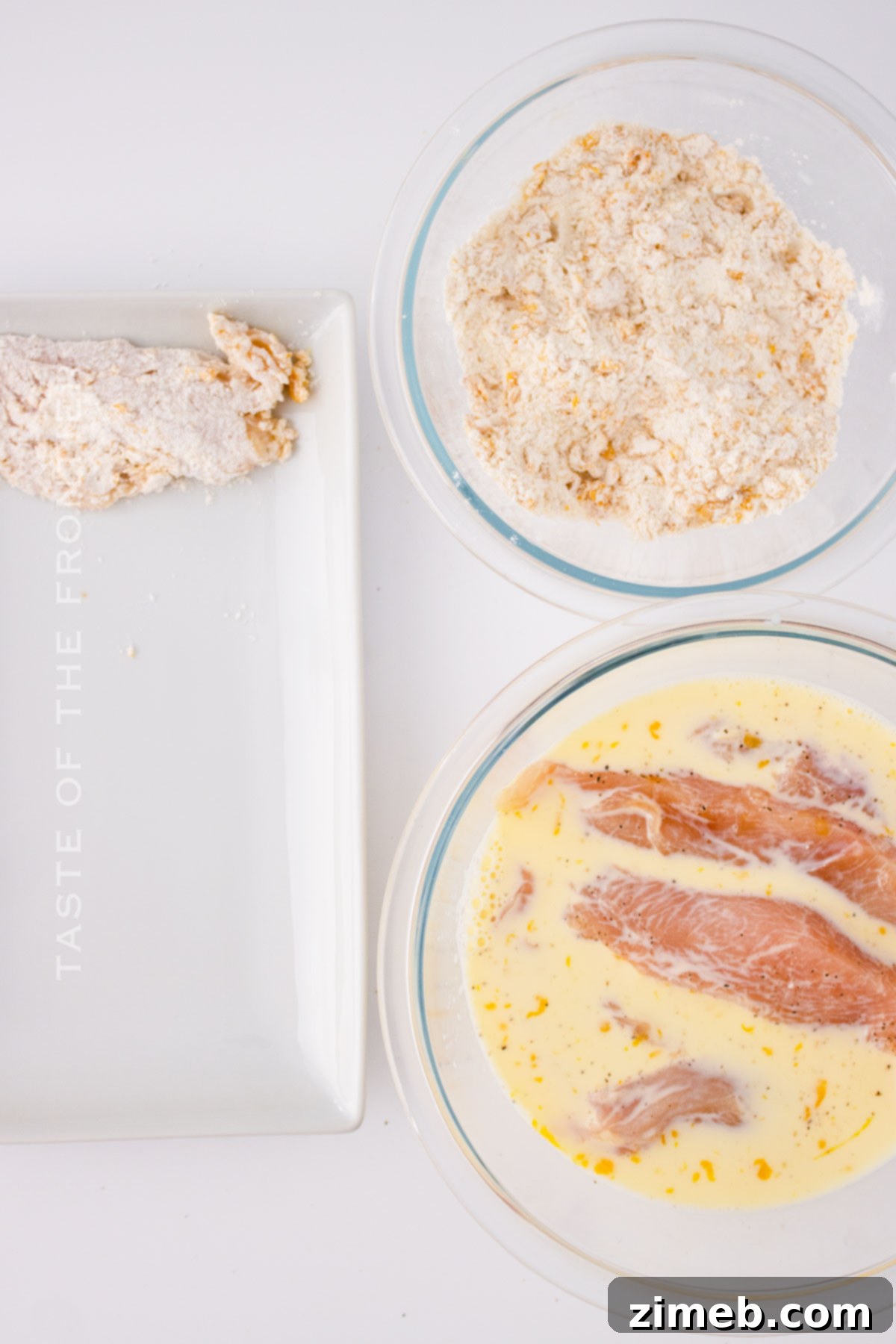 Close-up of chicken strips being breaded for the Oriental Chicken Salad, coated in cornflake mixture.