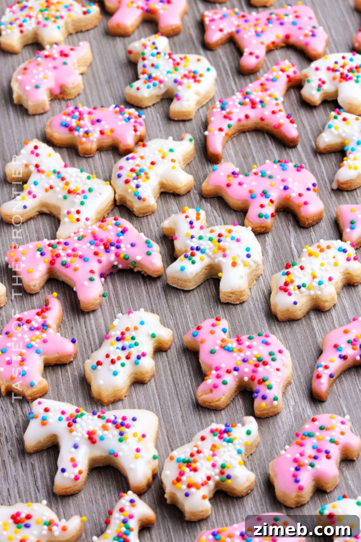 Whimsical Frosted Animal Treats 16 Pink and white frosted animal cookies with rainbow sprinkles on a plate.