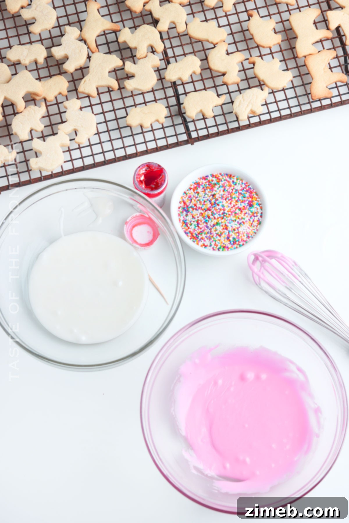 Whimsical Frosted Animal Treats 10 A plate of freshly baked pink and white frosted animal cookies with sprinkles.