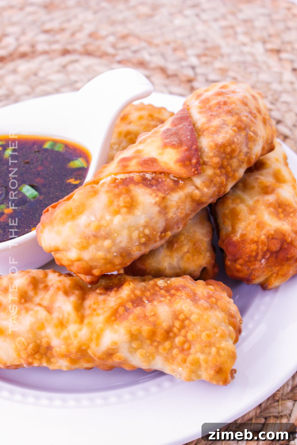 Crispy chicken egg rolls cooked in an air fryer, served with a sweet and savory dipping sauce, perfect as an appetizer.
