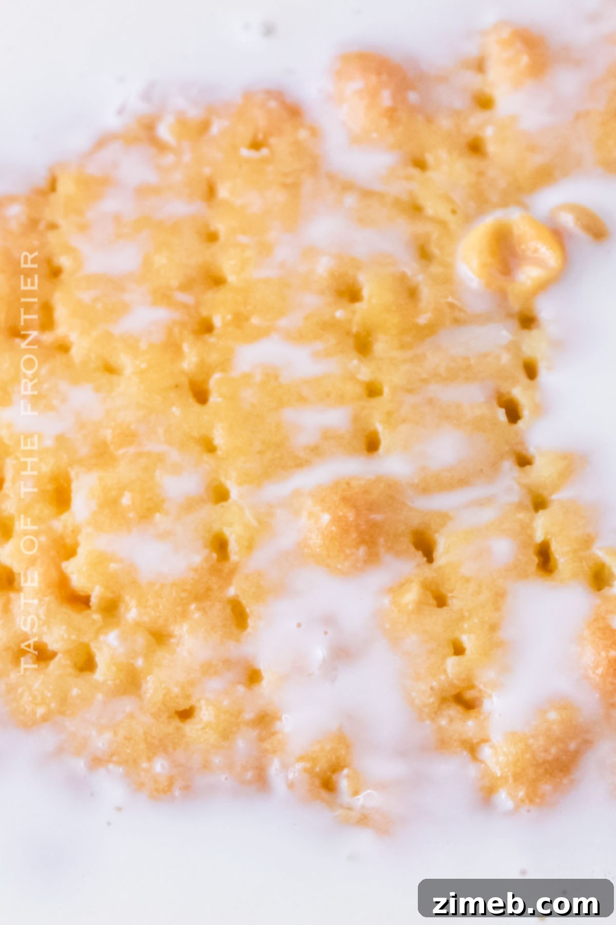 A fork poking holes into a freshly baked sponge cake, preparing it for the milk soak.