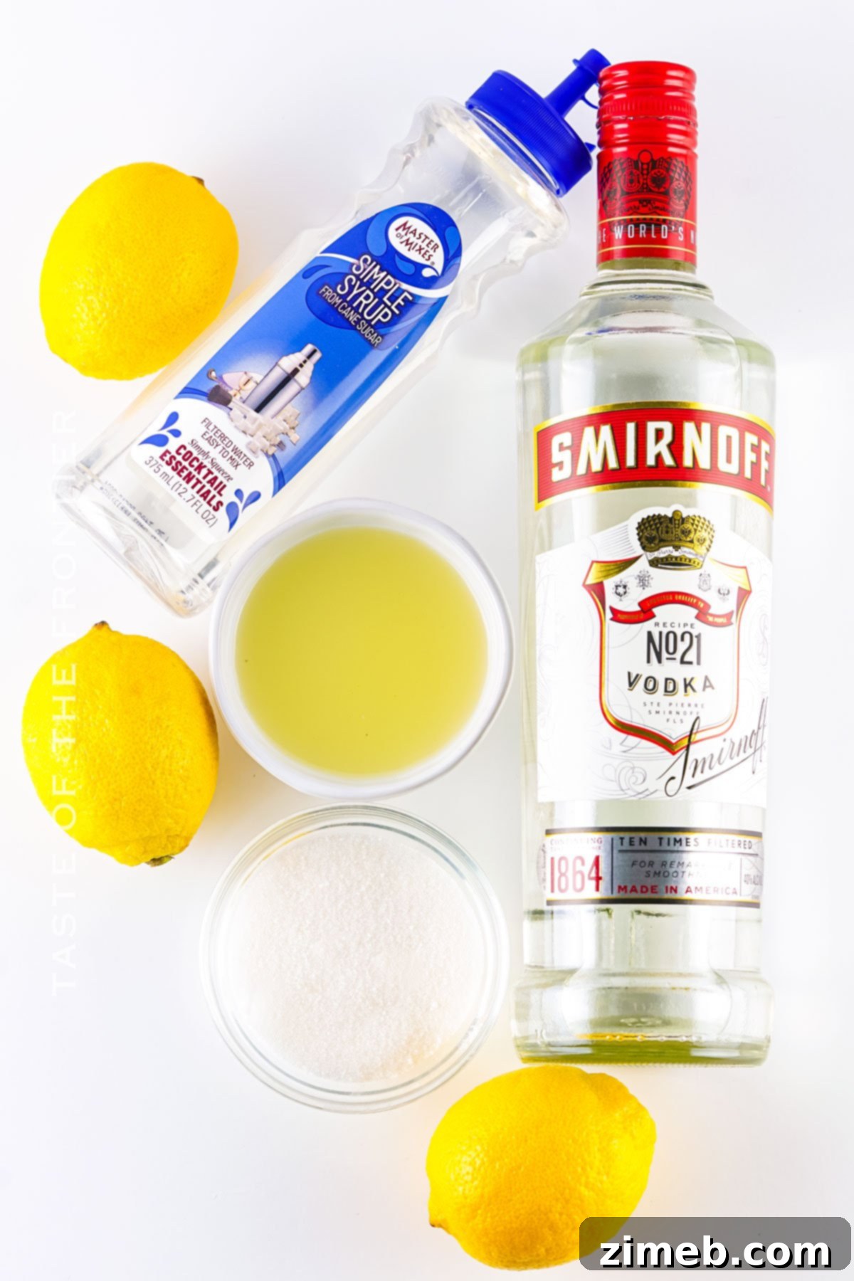Key ingredients for making delicious Lemon Drop Shots: vodka, fresh lemons, and simple syrup laid out on a clean surface.