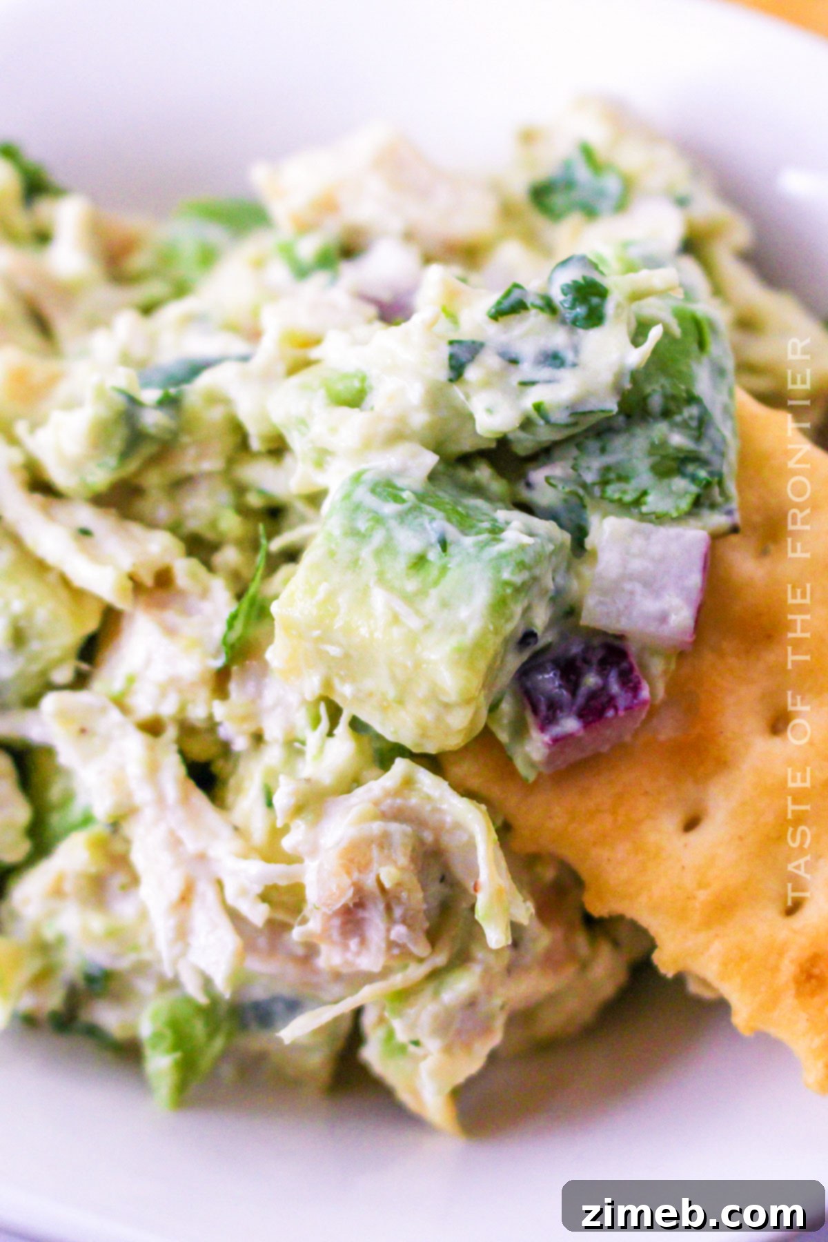 Easy Creamy Avocado Chicken Salad 3 Close-up of creamy avocado and chicken salad in a bowl, garnished with fresh cilantro.