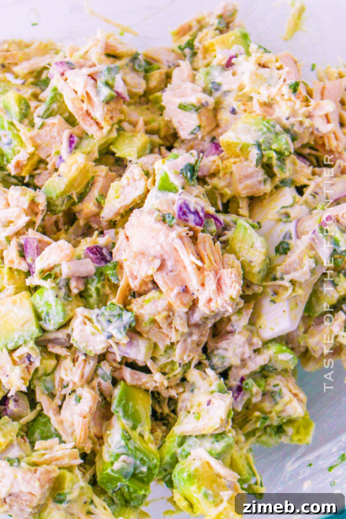 Easy Creamy Avocado Chicken Salad 9 Finished Avocado Chicken Salad in a bowl with a serving spoon, garnished with cilantro.