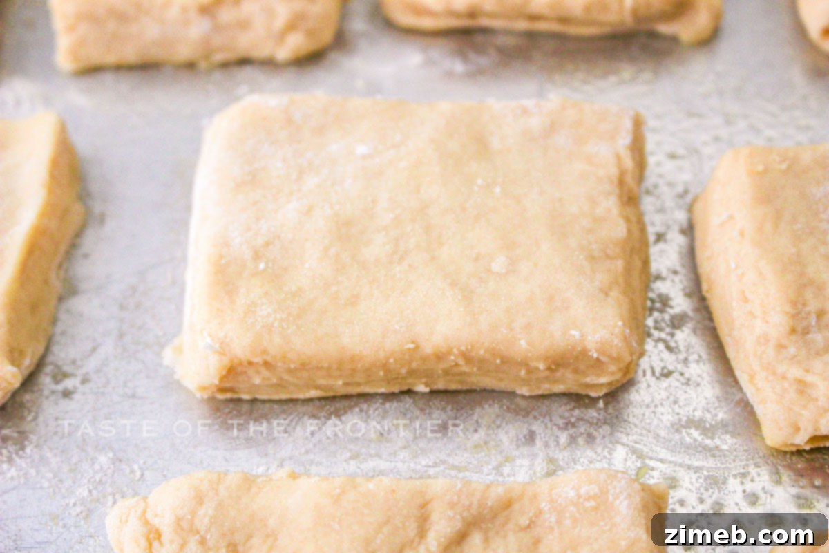 Homemade Texas Roadhouse Rolls 6 cutting and rising dough - Dough rectangles rising on a baking sheet.