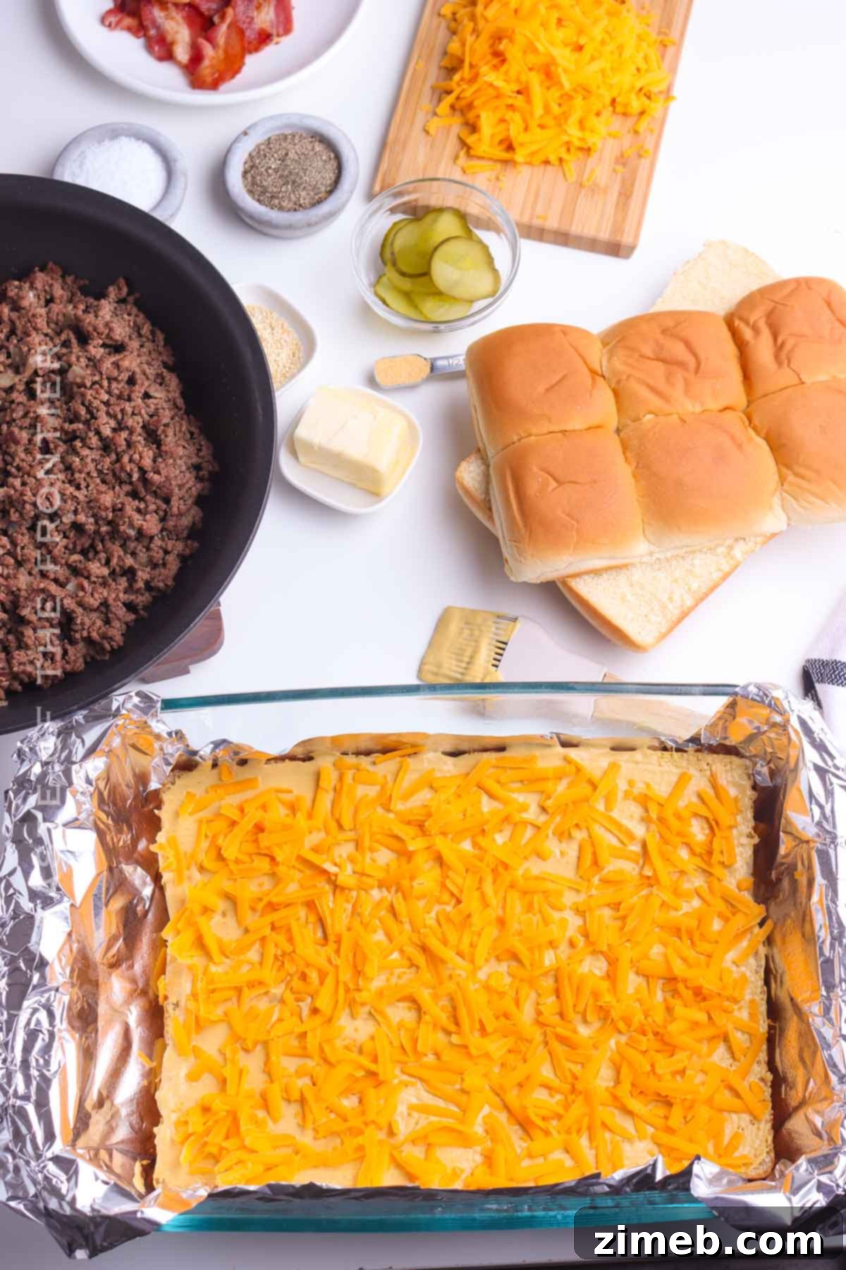 Sweet Hawaiian Cheeseburger Sliders 6 Close-up of assembling Cheeseburger Sliders in a baking dish.