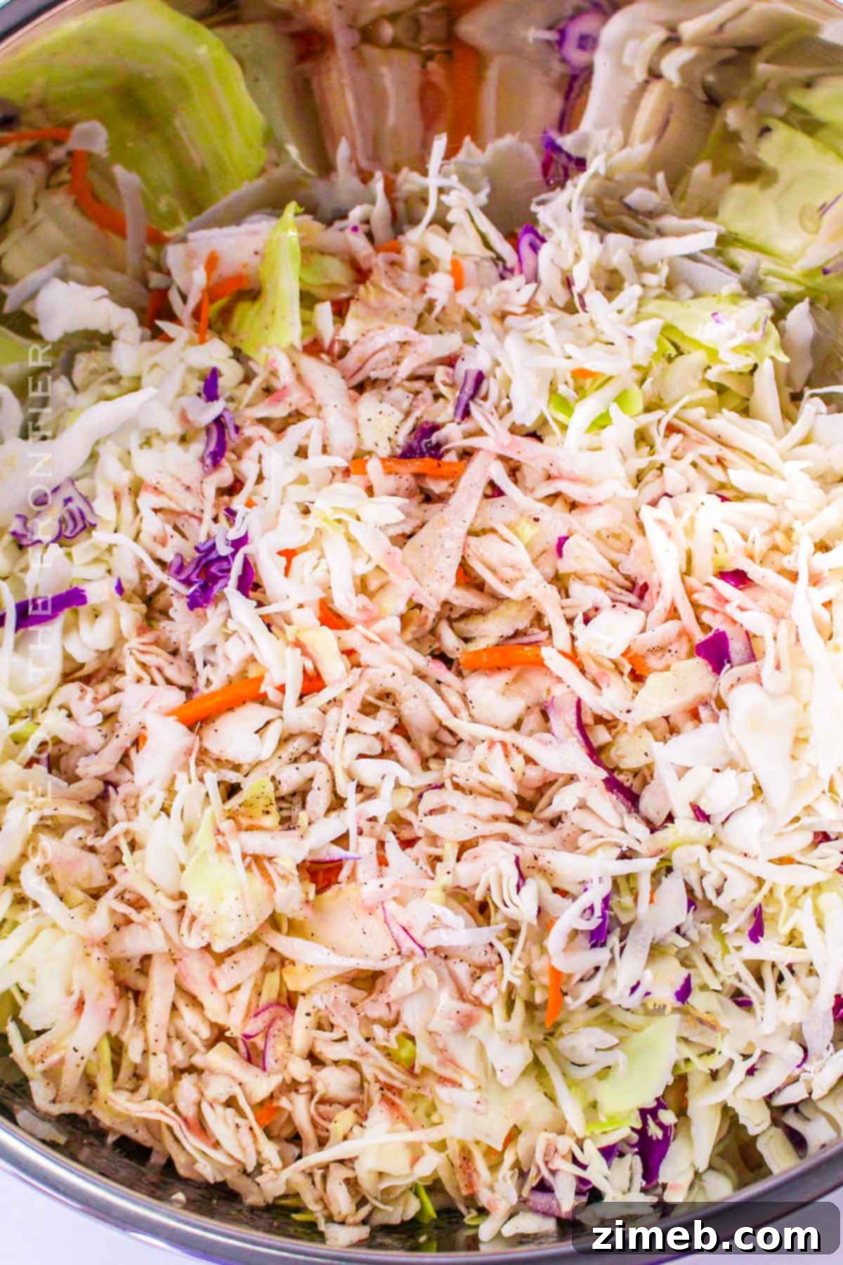 Zesty Red Wine Vinegar Coleslaw 6 Hands tossing Red Wine Vinegar Coleslaw in a large mixing bowl, showing the fresh ingredients.