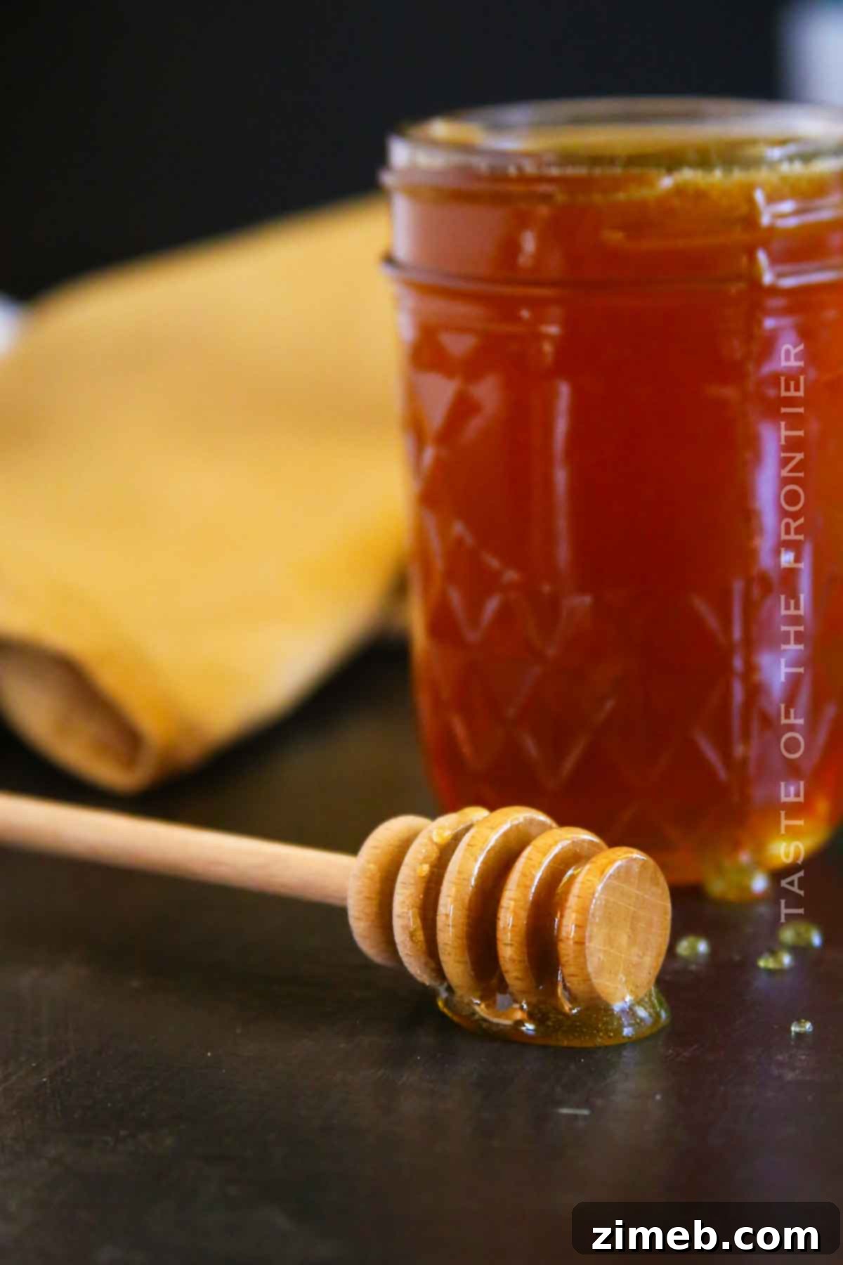 Embered Nectar 9 Honey wand dipping into a jar of smoked honey, showing its smooth consistency