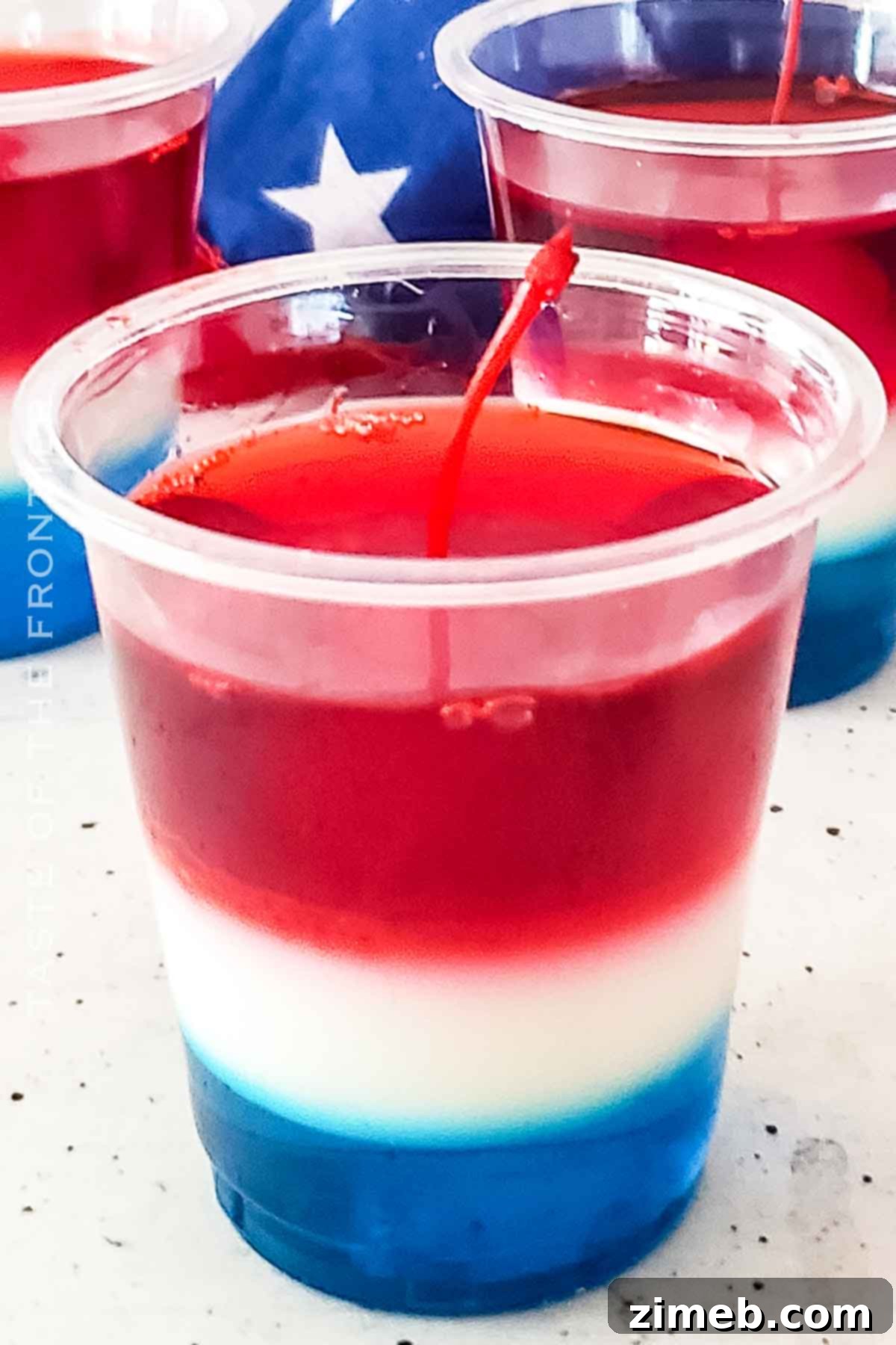 A vibrant selection of layered jello treats, including the red, white, and blue Bomb Pop Jello Shots, perfect for holidays.