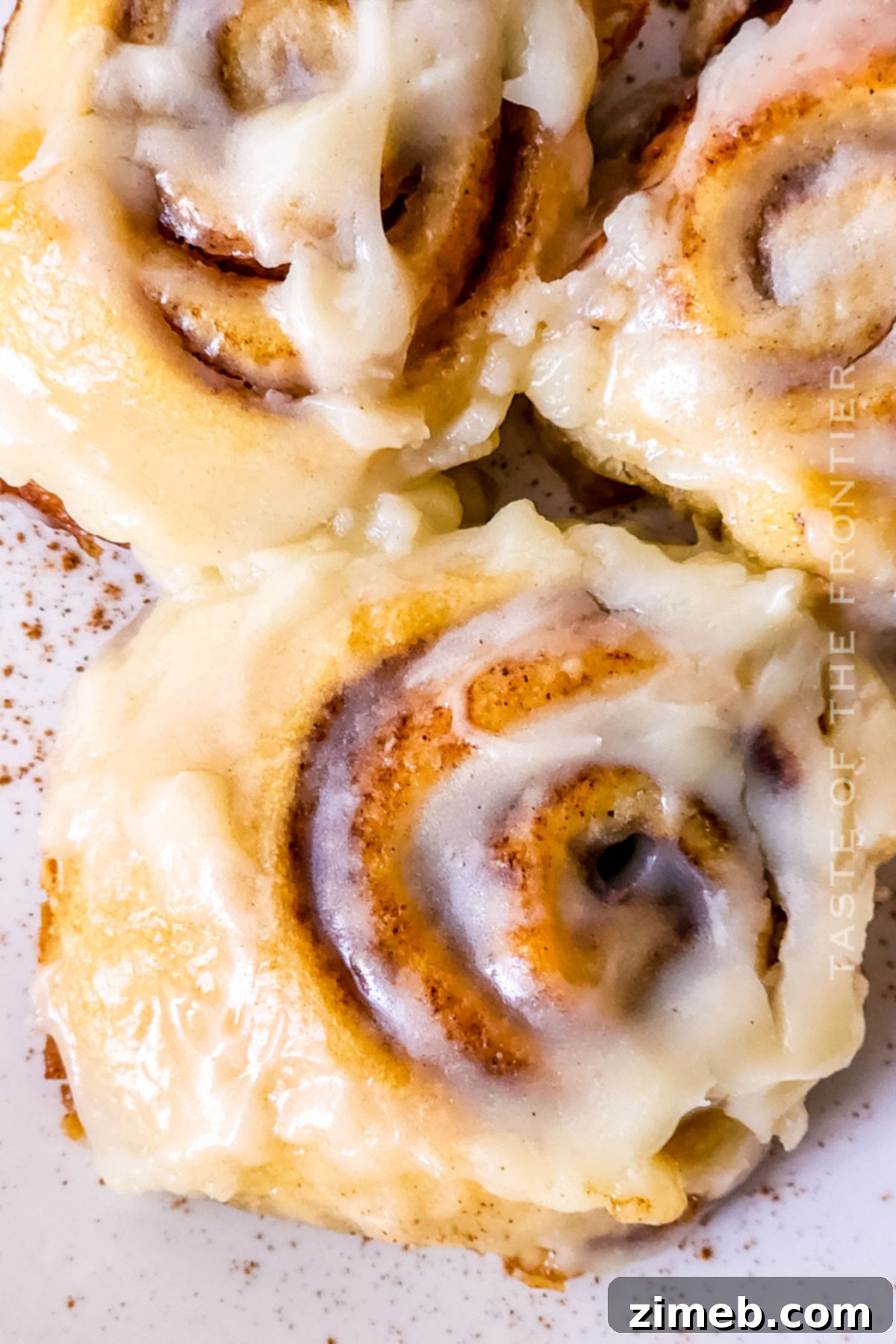 Close-up of creamy cream cheese frosting on a cinnamon roll, ready to be spread.