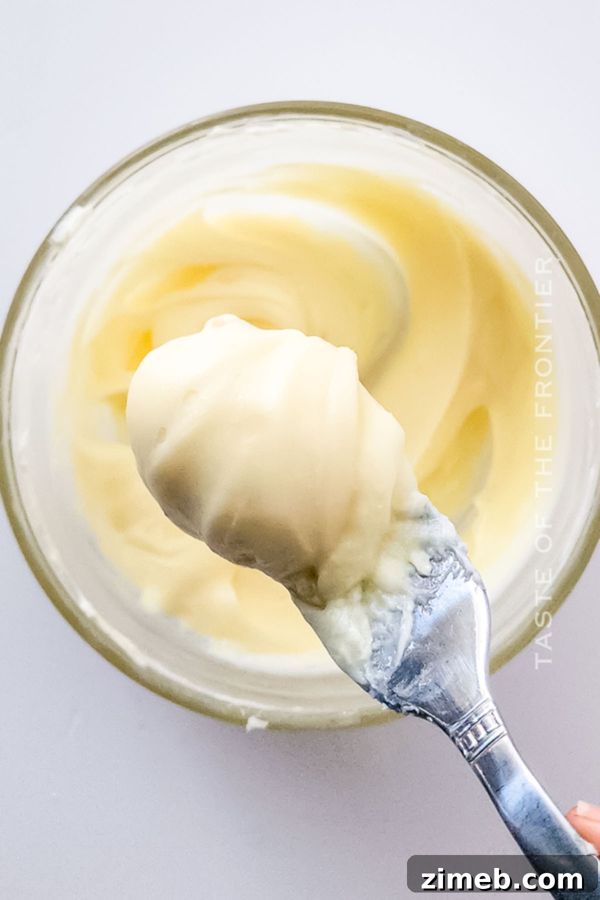 Close-up of a warm cinnamon roll coated in thick, luscious cream cheese icing, ready to be eaten.