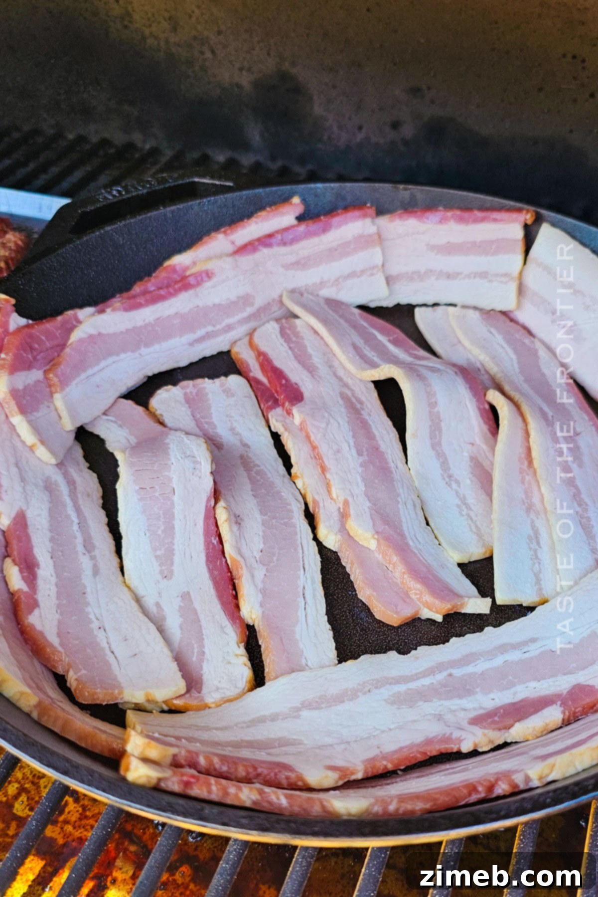 Gourmet Smoked Bacon 5 Bacon cooking in a cast iron skillet inside a Traeger smoker, infusing with smoky flavor.