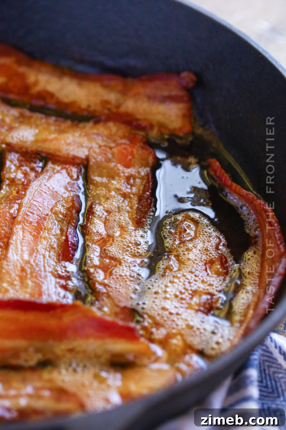Gourmet Smoked Bacon 9 Close-up of crispy, golden-brown smoked bacon sizzling in a cast iron skillet on a pellet grill.