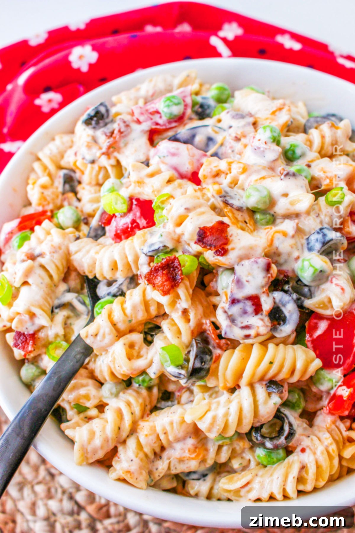 A serving of Bacon Ranch Pasta Salad in a white bowl, garnished with fresh herbs.