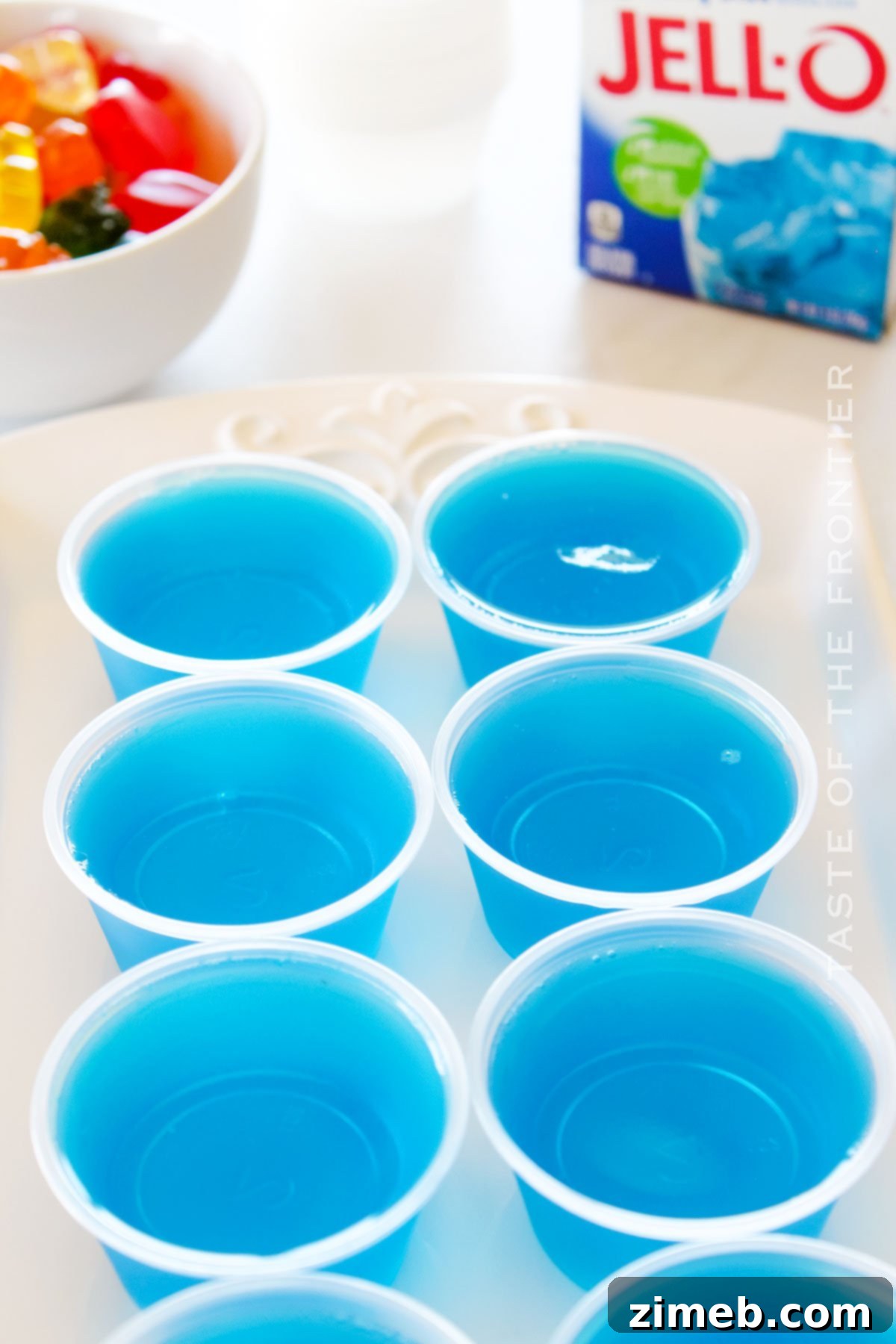 Finished blue jello treats in shot cups with gummy toppings.