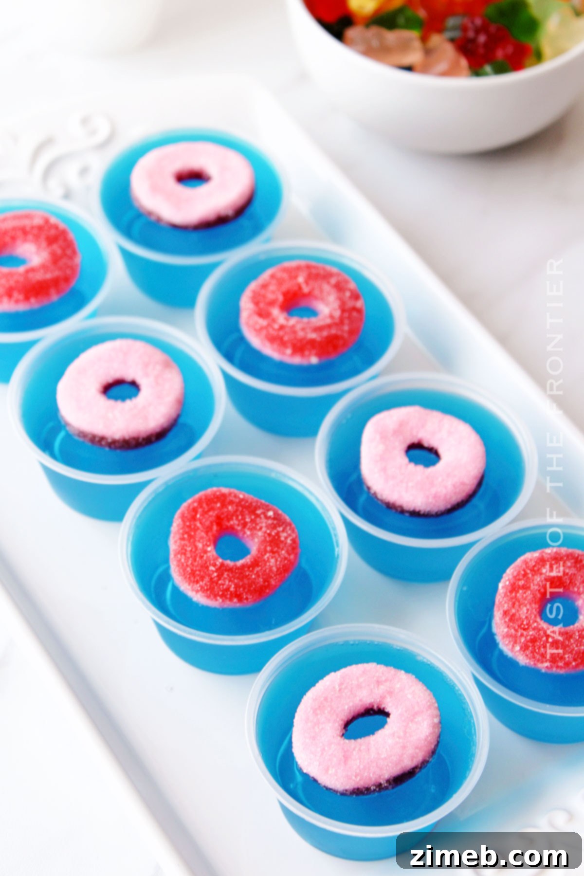 Adding gummy rings and bears to Pool Party Jello Shots before serving.