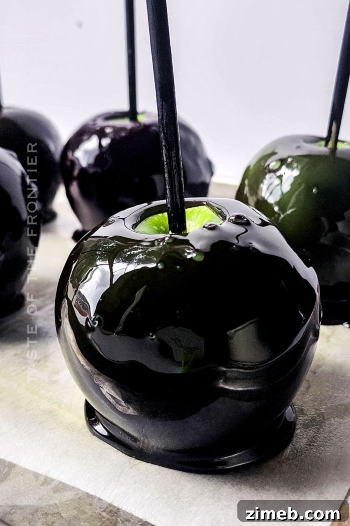Midnight Candy Apples 7 Black Candy Apples cooling and hardening on parchment paper.