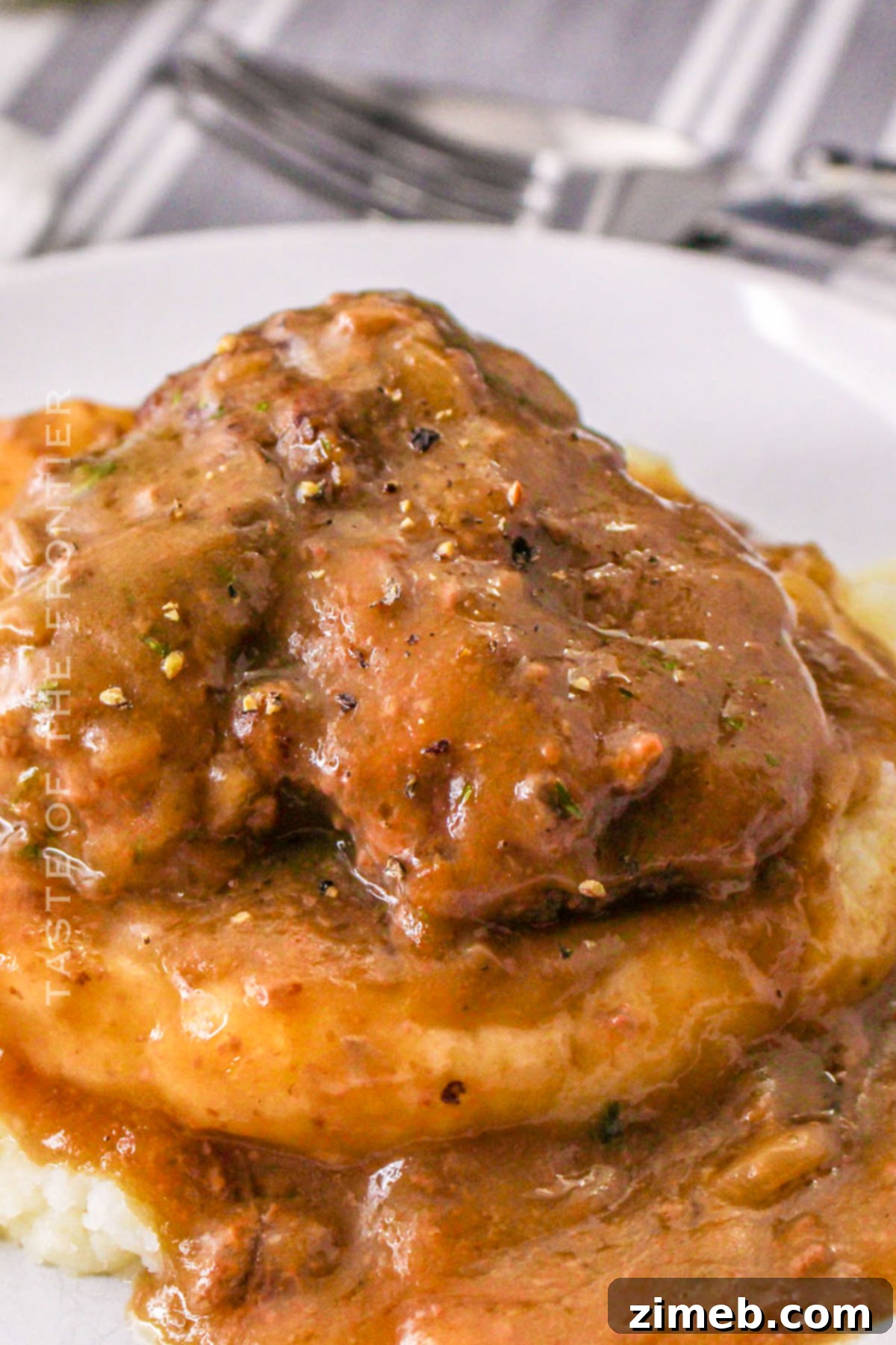 Tender Slow Cooker Cube Steak 3 Crock Pot Cubed Steak Recipe - Close-up of cooked beef patties simmering in a rich, thick gravy, ready to be served.