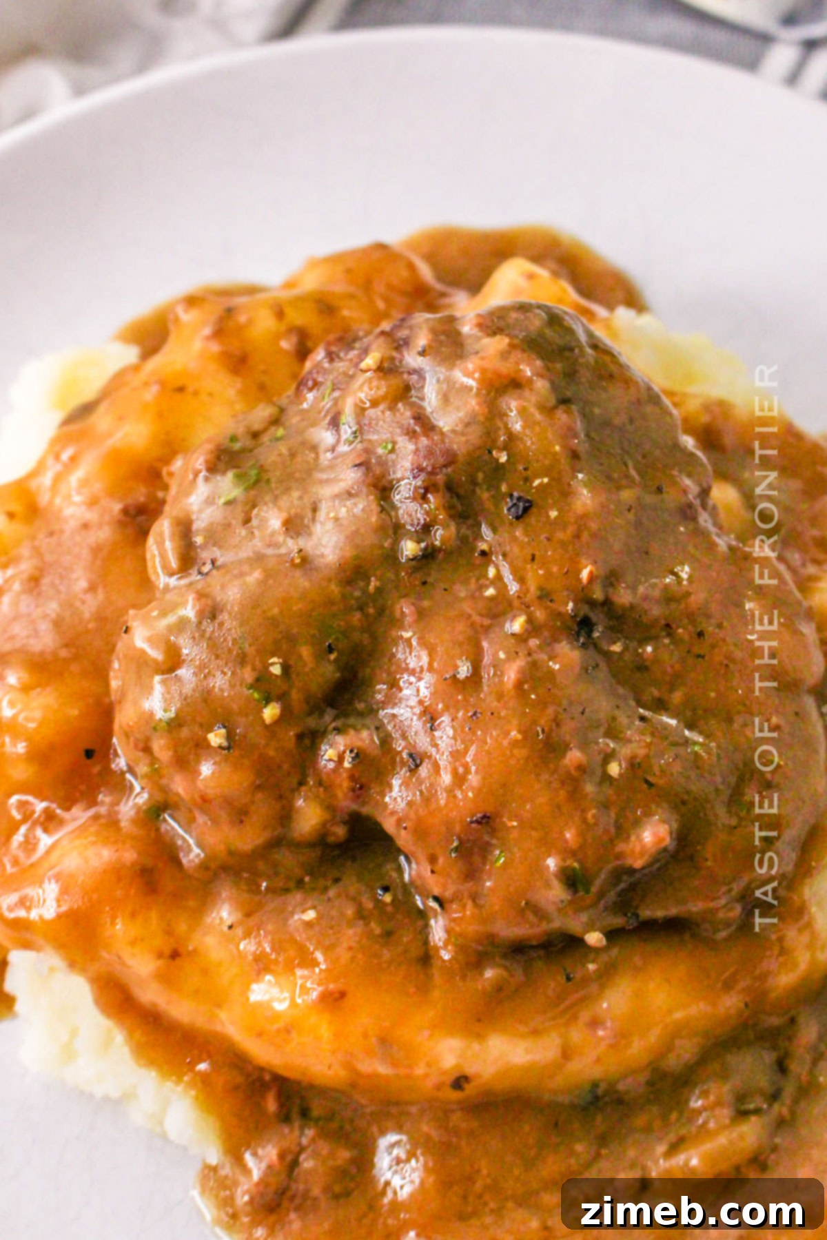 Tender Slow Cooker Cube Steak 6 Chopped Steak Dinner - A close-up of Crock Pot Cubed Steak served on a plate with mashed potatoes and green beans.