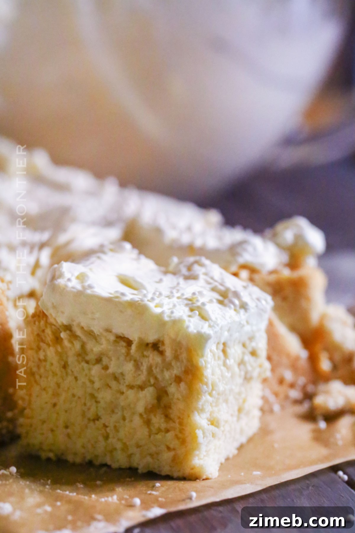 A large slice of White Chocolate Mud Cake on a plate, garnished with white pearl sprinkles.