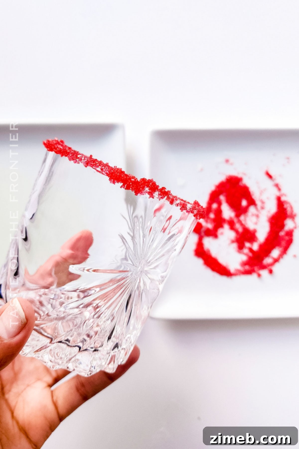 Detail of a glass rimmed with red sugar for Grinch Cocktail / non-alcoholic Grinch Punch
