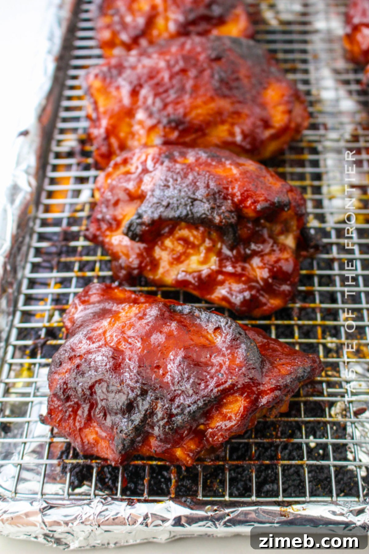 Oven Baked BBQ Chicken Thighs 3 Close-up of chicken thighs baking in the oven, coated in BBQ sauce for a delicious meal.