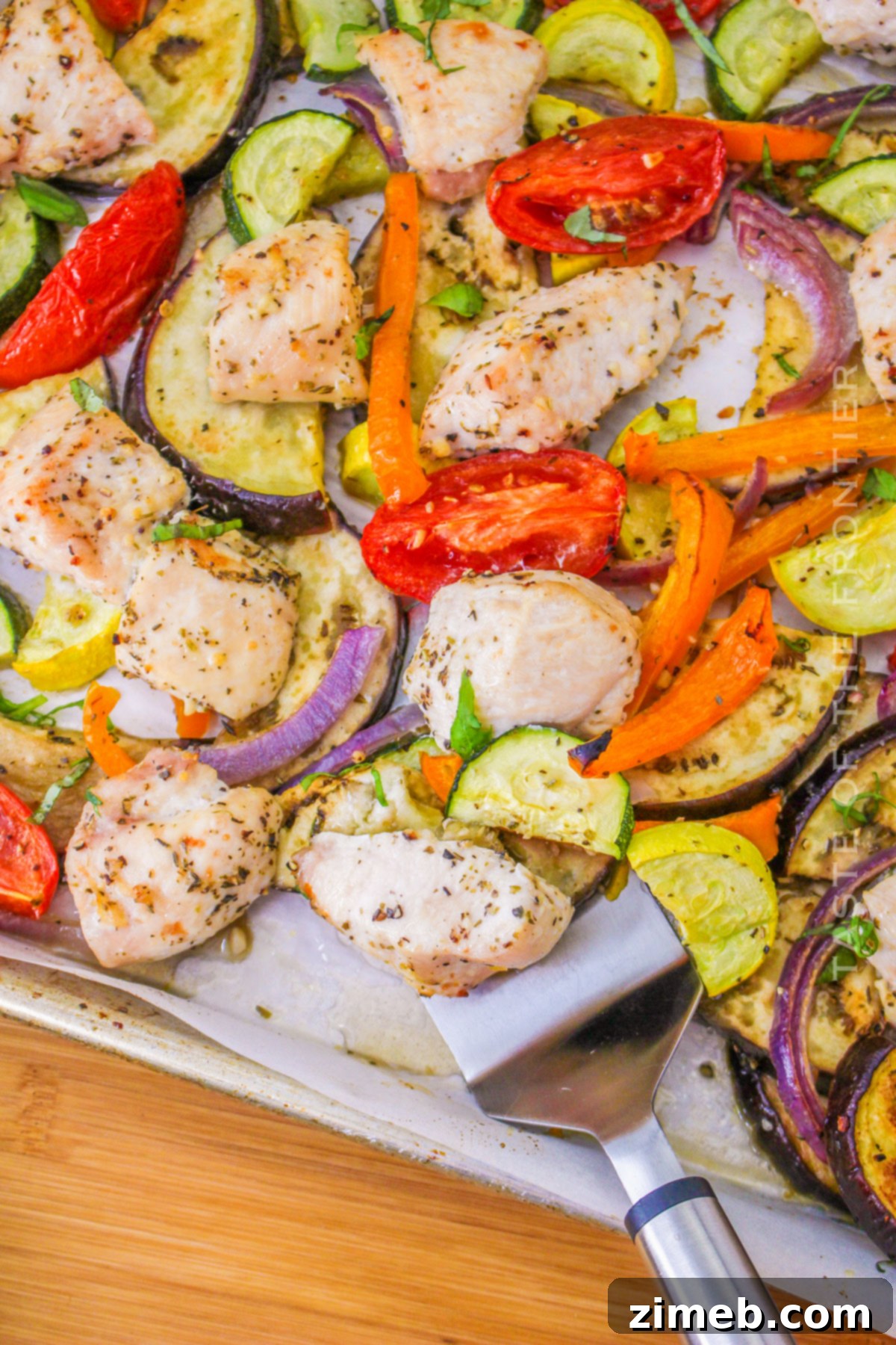 A completed sheet pan dinner with chicken and colorful ratatouille