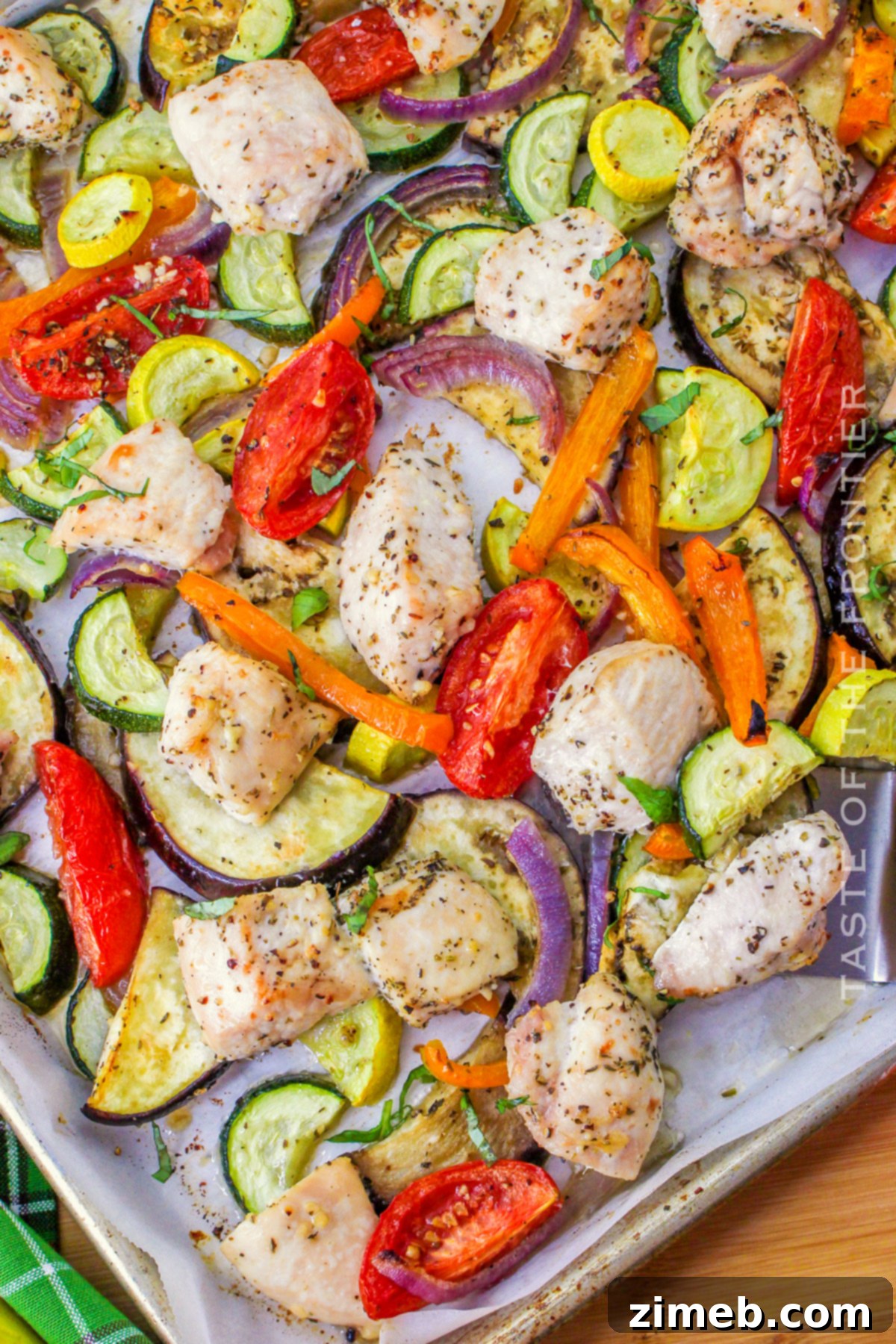 Close up of roasted chicken and ratatouille vegetables on a sheet pan