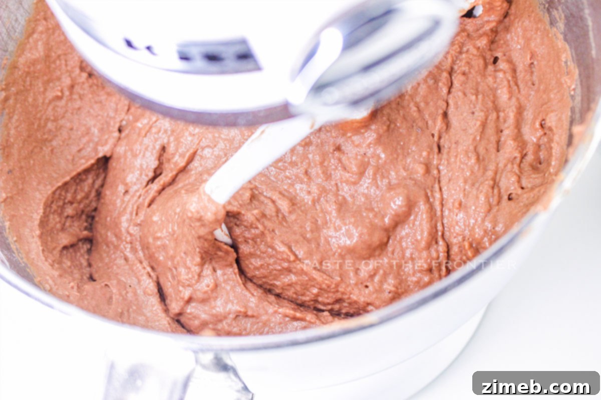 Hands cutting chocolate beignet dough into rectangles on a floured surface