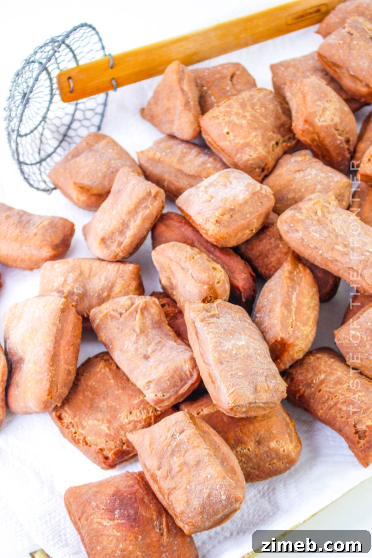 Freshly fried chocolate beignets draining on a wire rack with a paper towel underneath