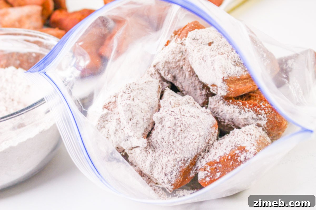 Close-up of chocolate beignets dusted generously with chocolate powdered sugar