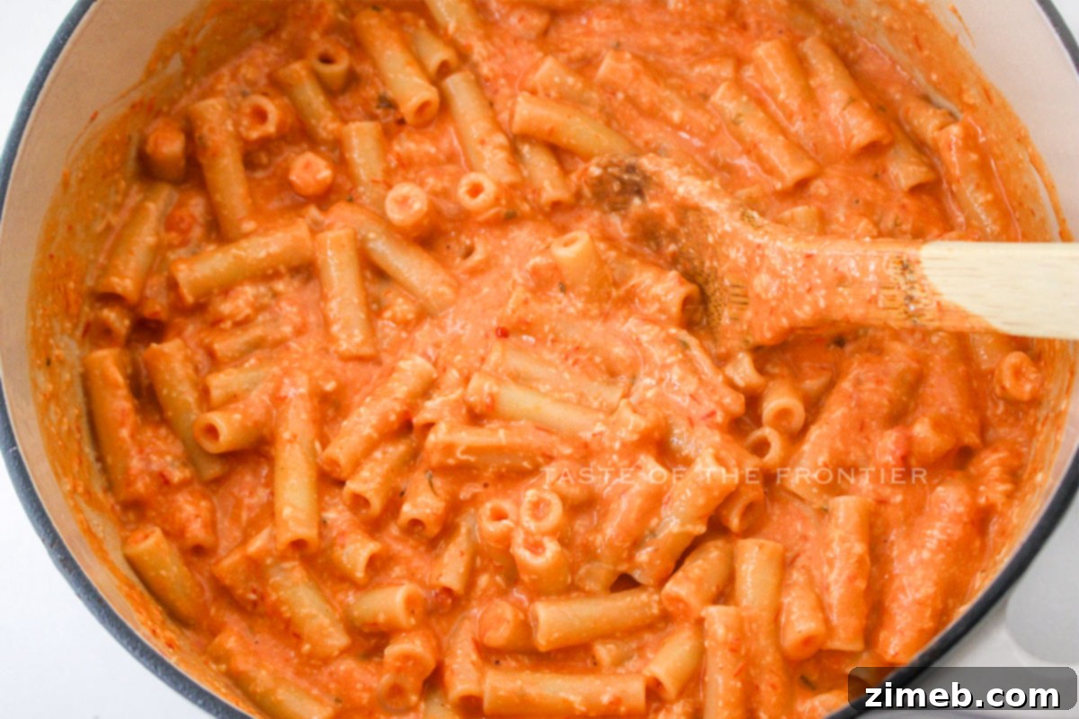 Mixing the pasta with the creamy cheese sauce for Five Cheese Ziti al Forno