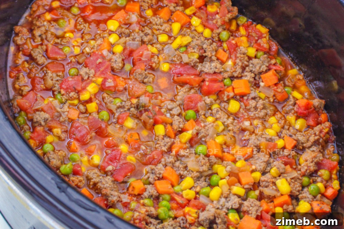 Slow Cooker Shepherd's Pie 6 Adding browned meat and vegetables to the slow cooker for Shepherd's Pie.