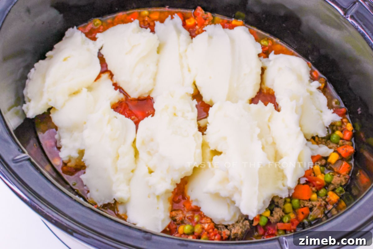 Slow Cooker Shepherd's Pie 7 Applying creamy mashed potato topping to the slow-cooked Shepherd's Pie.
