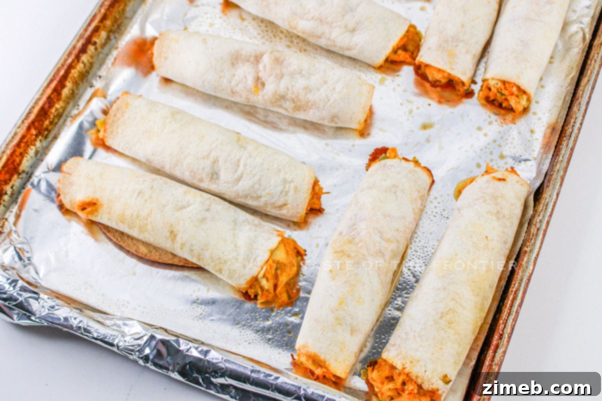 Crispy Buffalo Chicken Taquitos 14 Baked Buffalo Chicken Taquitos, golden and crispy, on a serving plate