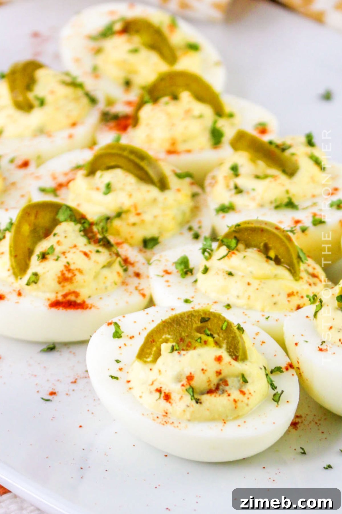 Zesty Jalapeño Deviled Eggs 2 Jalapeno Deviled Eggs arranged on a platter, garnished with fresh cilantro and paprika, showcasing the vibrant green and creamy yellow filling.