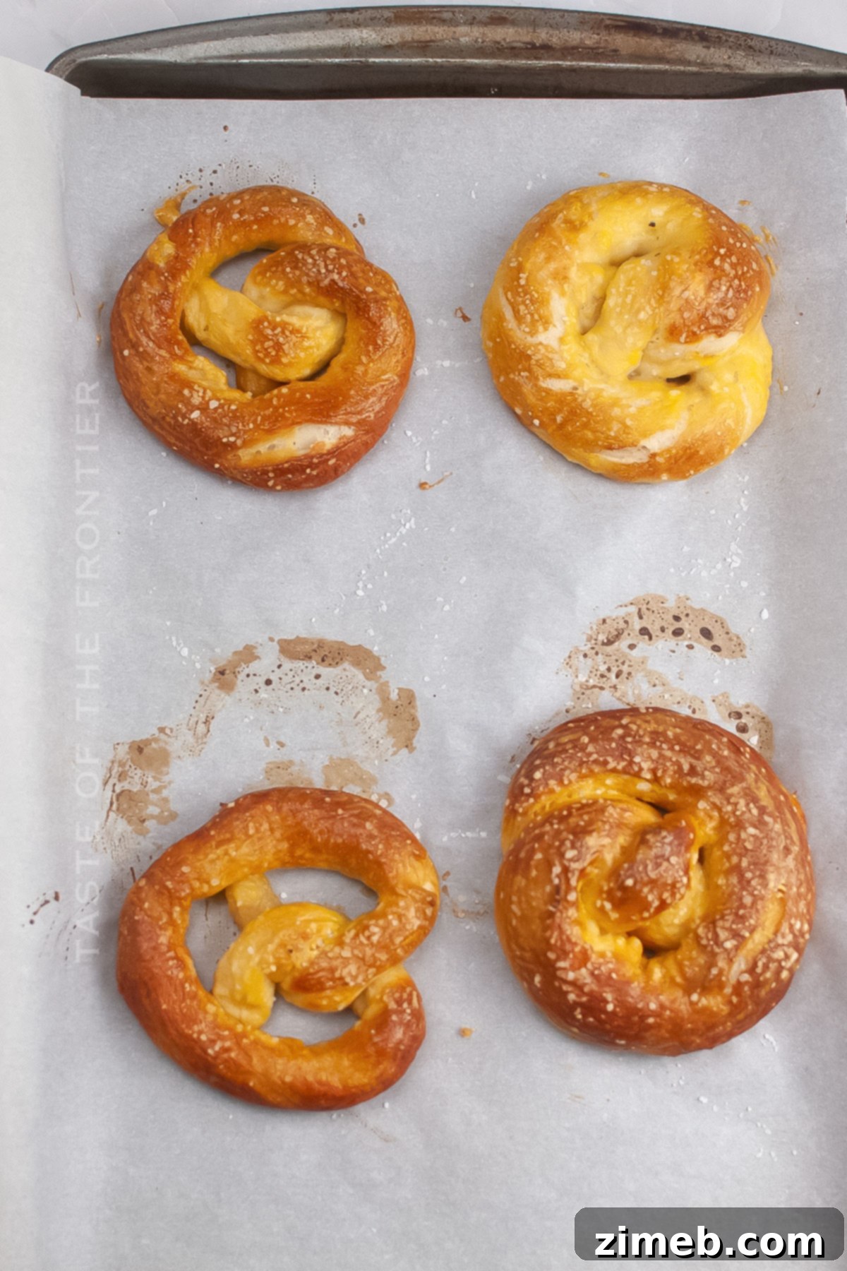 Artisan Sourdough Pretzels 8 Freshly baked soft pretzels with coarse salt on a baking sheet.