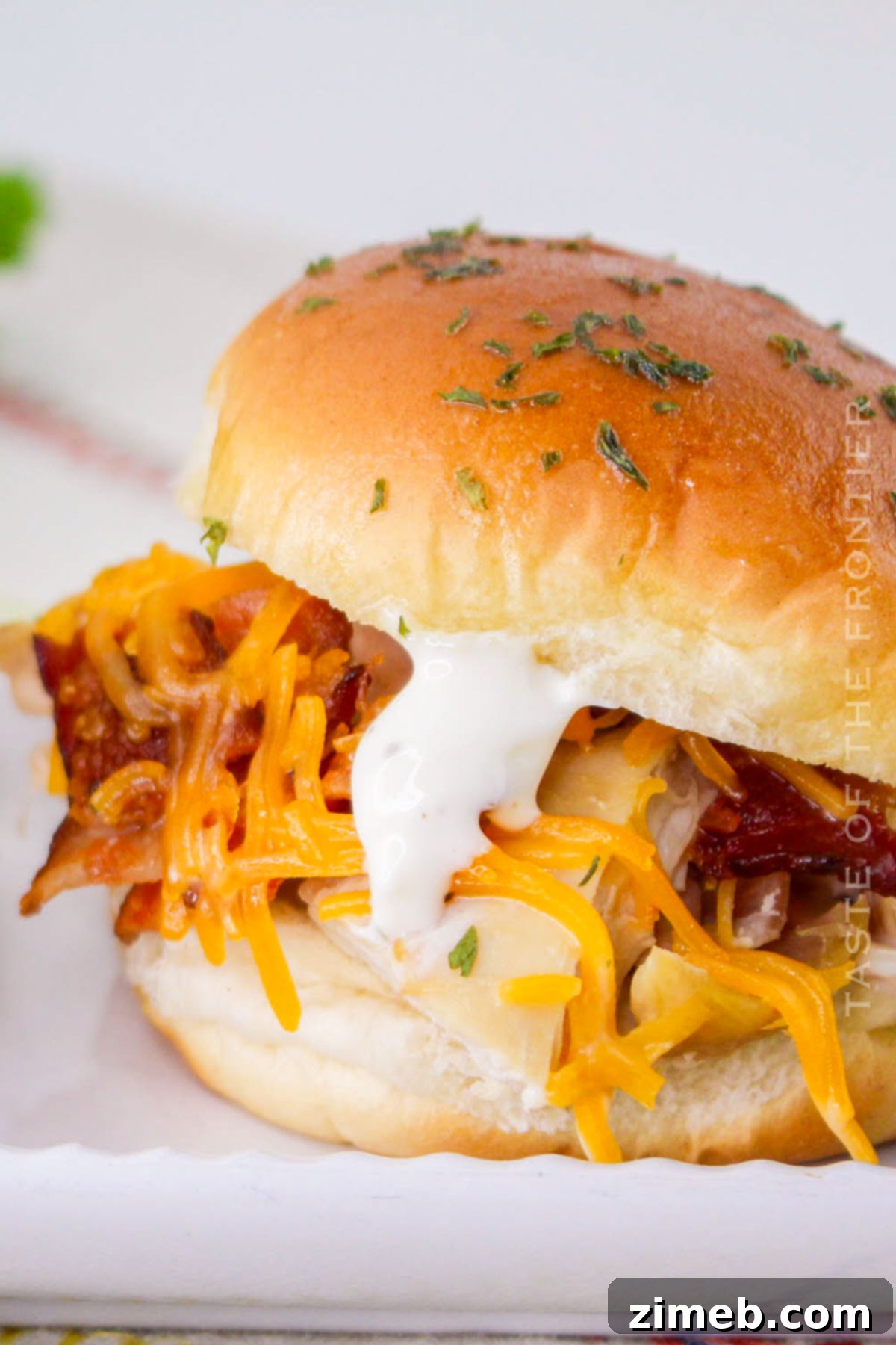 Ultimate Bacon Ranch Chicken Sliders 3 Bacon Chicken Ranch Sliders recipe - an overhead view of sliders arranged on a serving board with a side of ranch dressing.