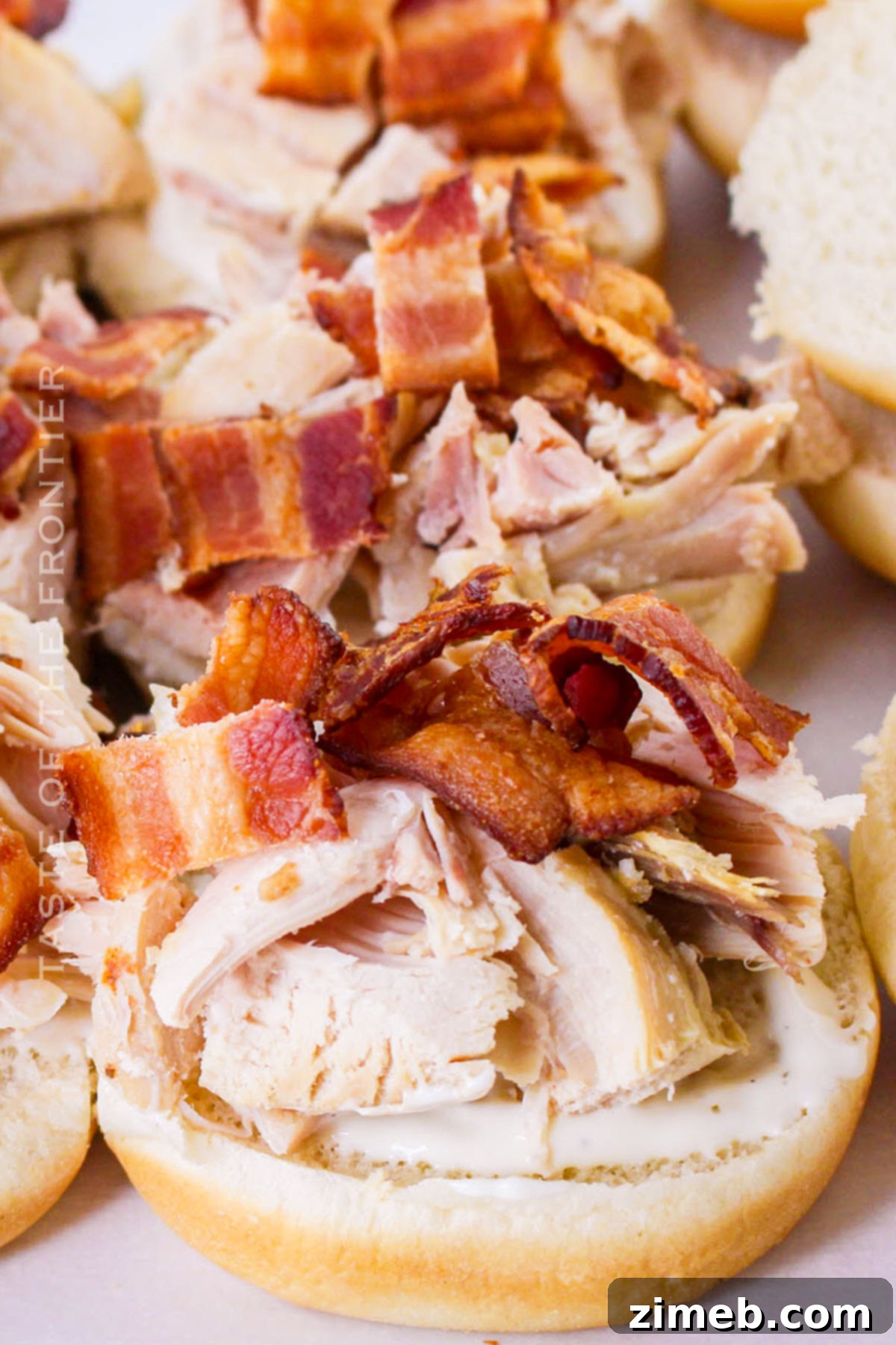 Ultimate Bacon Ranch Chicken Sliders 6 chicken sandwich with bacon - a close-up of a single Bacon Chicken Ranch Slider, highlighting the layers of chicken, bacon, and melted cheese.
