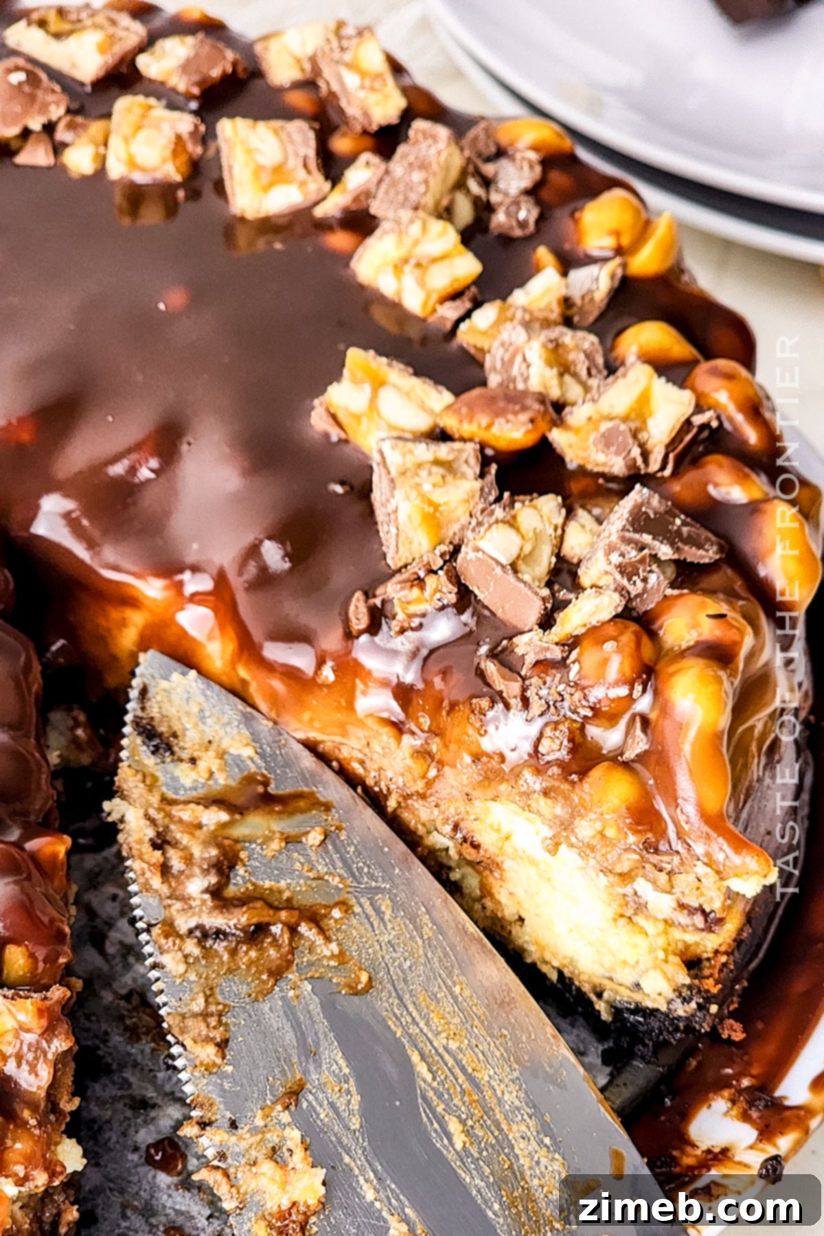 An irresistible Snickers cheesecake dessert slice on a plate, ready to be enjoyed.