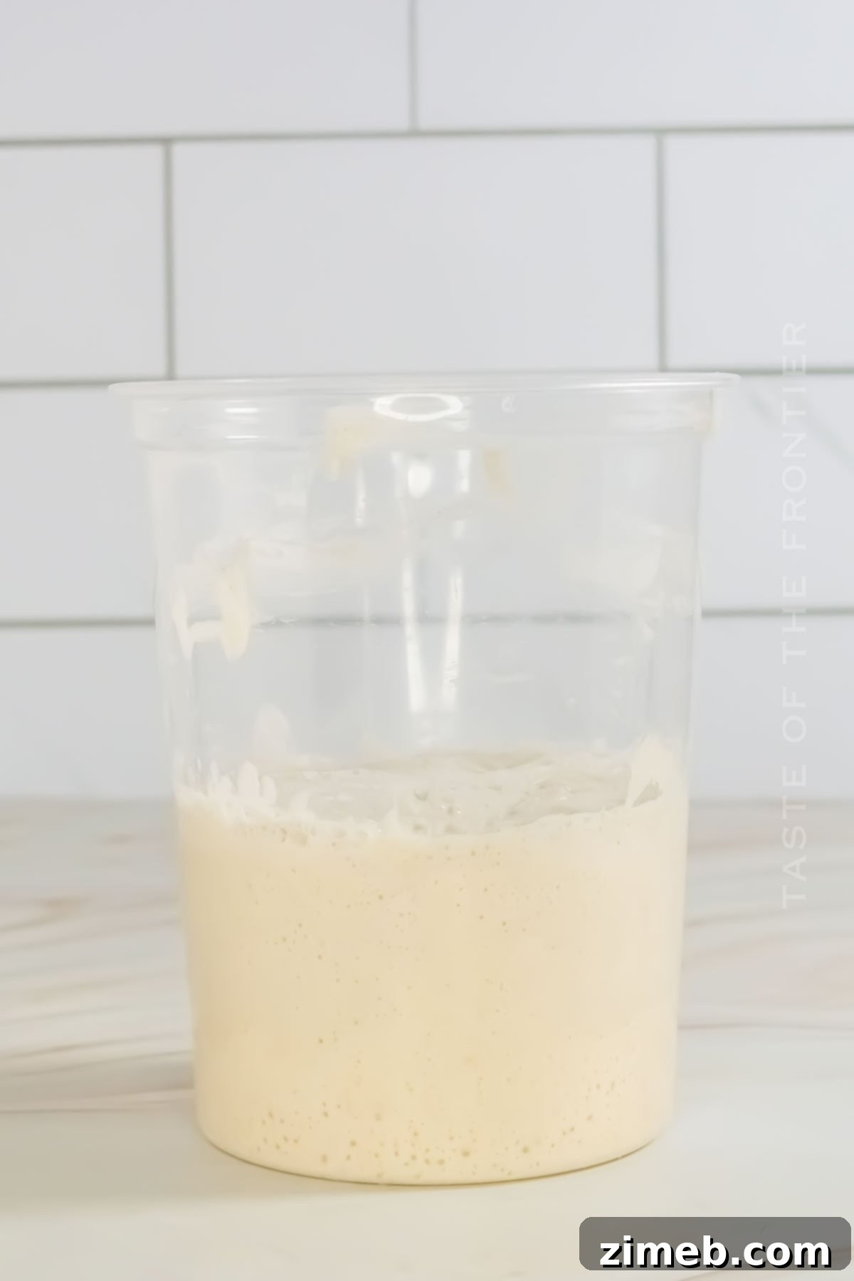 Bringing Your Sourdough to Life 6 Close-up of a sourdough starter actively bubbling and growing in a jar, marked with a rubber band.