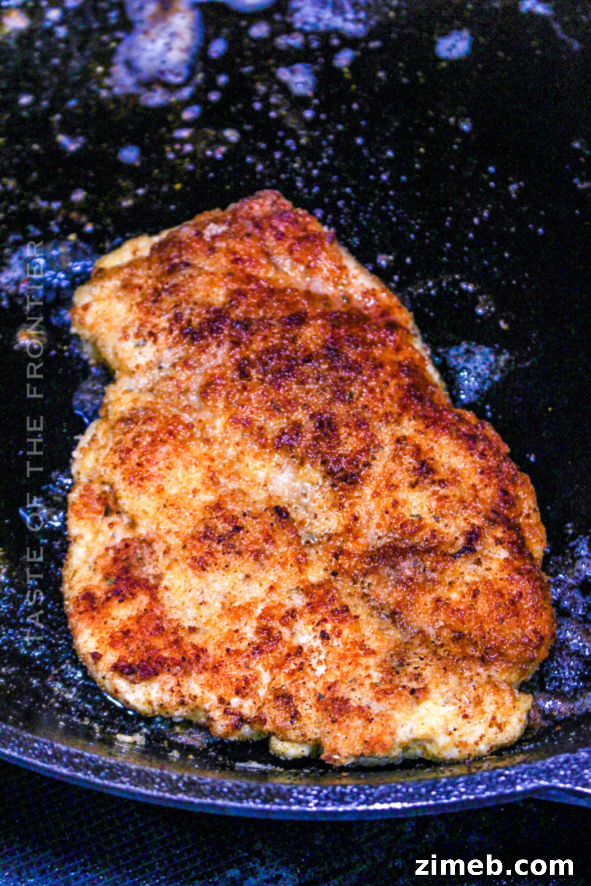 Chicken cutlets frying in a skillet with olive oil