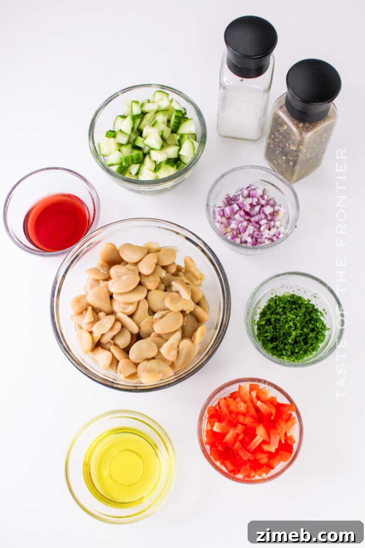 Fresh ingredients for Butter Bean Salad laid out on a cutting board, including butter beans, cucumber, bell pepper, and red onion.