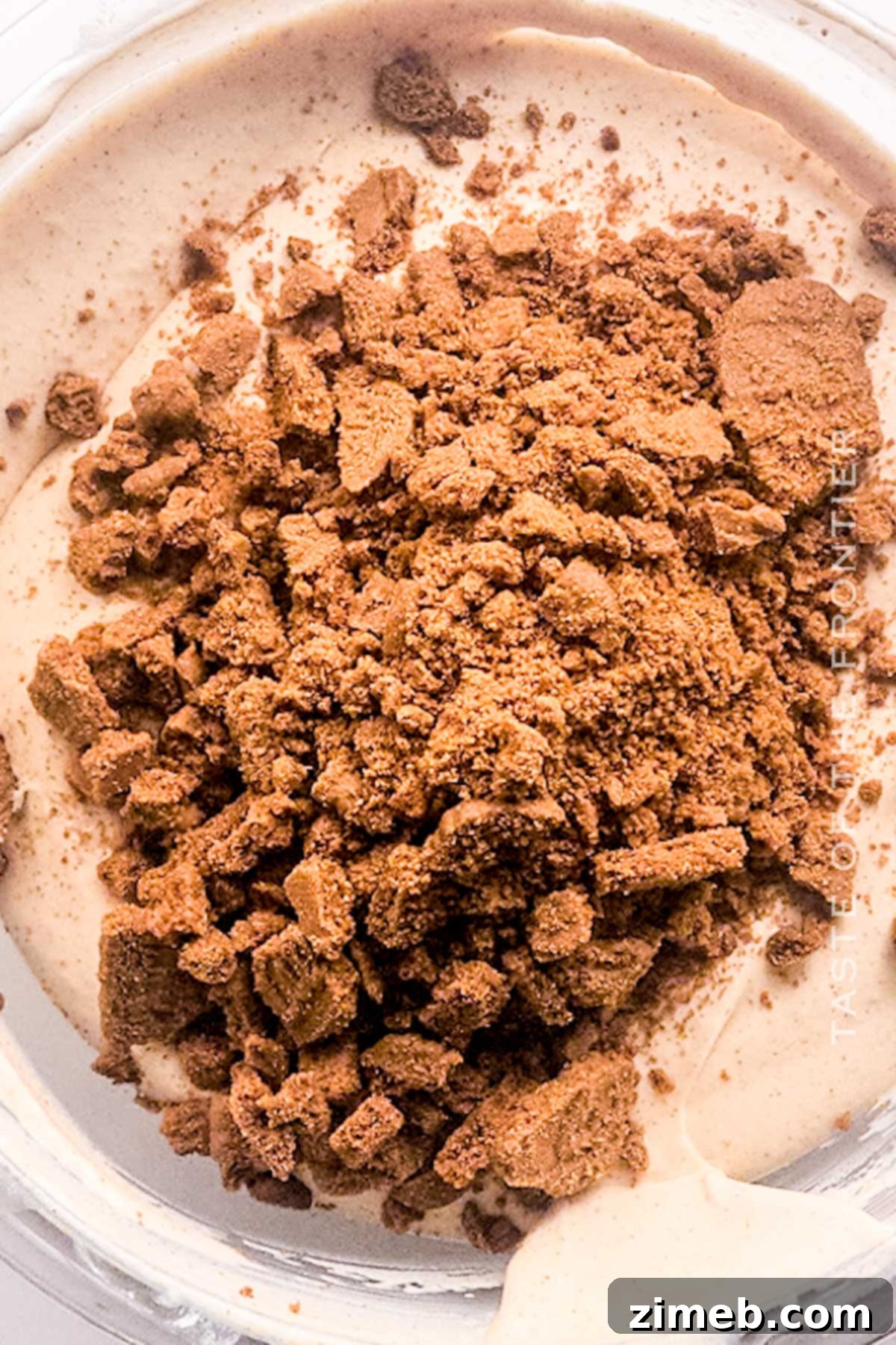 Folding in crushed Biscoff cookies into the pumpkin ice cream mixture