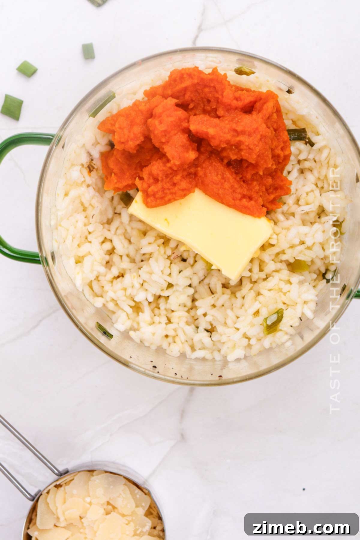 Velvet Pumpkin Risotto 6 A hand stirring pumpkin puree into a creamy risotto in a saucepan, showing the vibrant orange color mixing in.