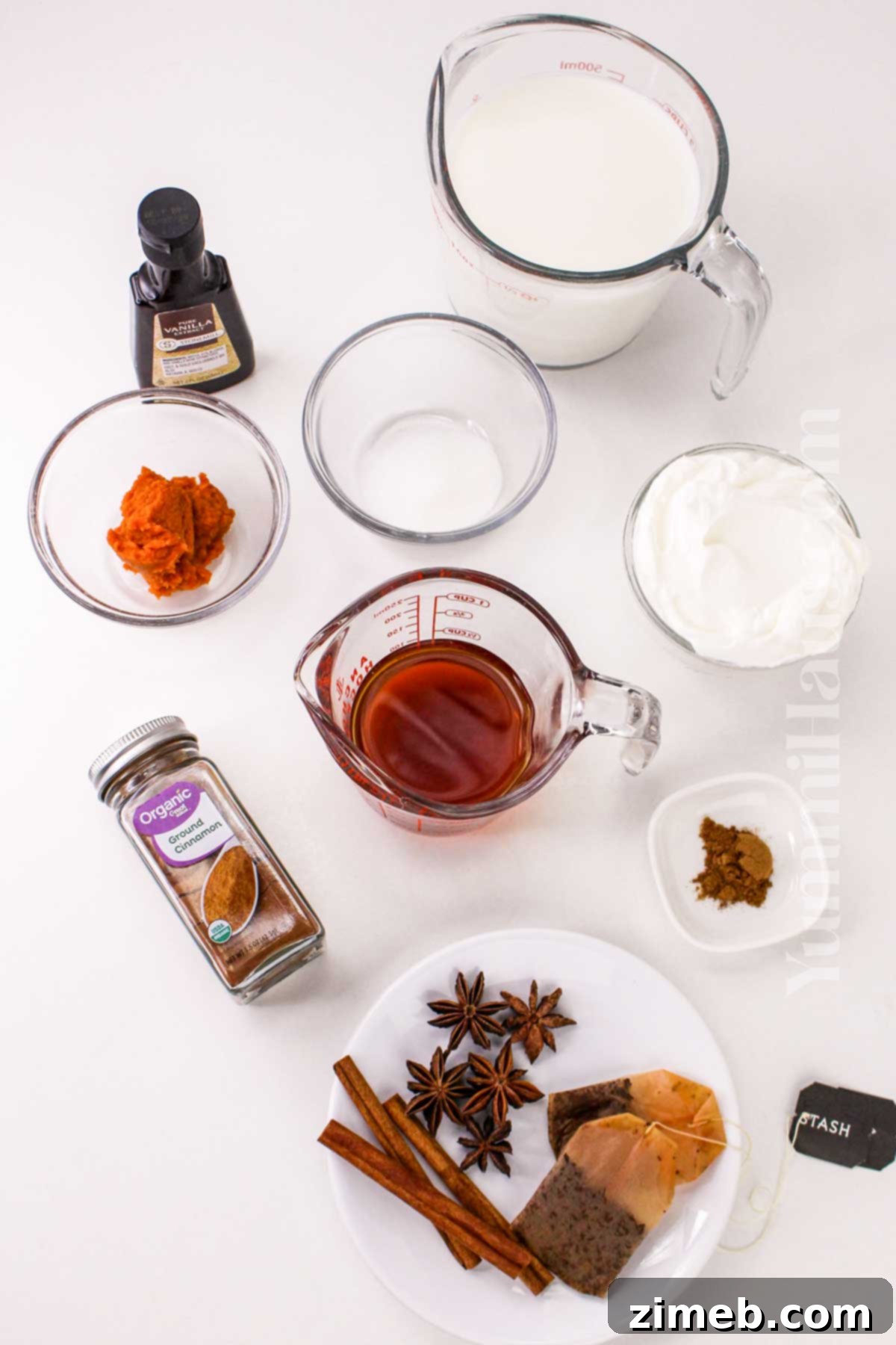 Autumn Pumpkin Chai Latte 3 Ingredients for homemade Pumpkin Spice Chai Latte laid out on a table, including milk, pumpkin puree, chai tea, and spices.
