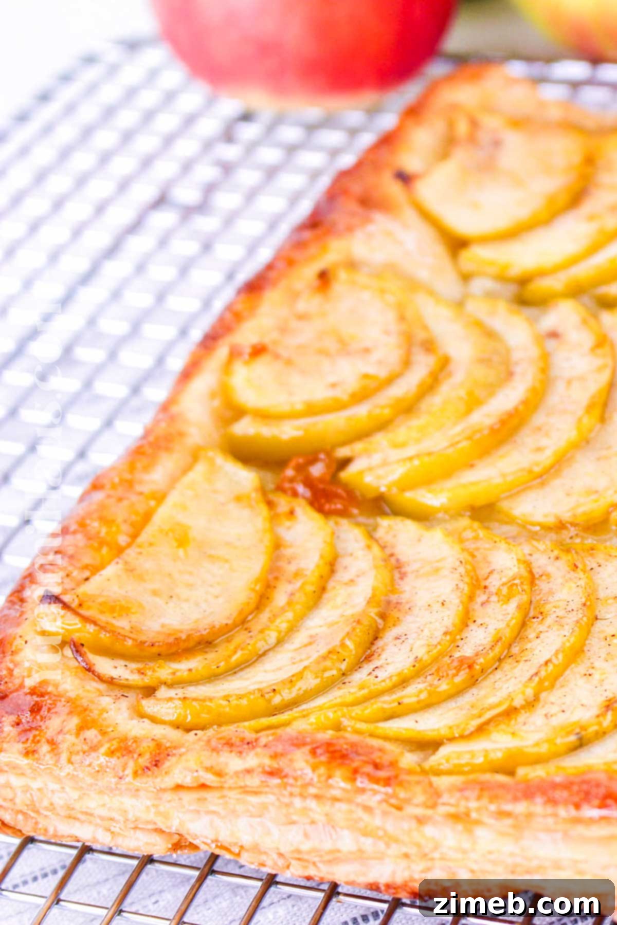 A freshly baked Apple Tart Using Puff Pastry, gleaming with apricot glaze, sliced and ready for serving.